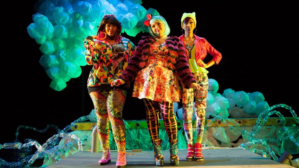 Three woman stand in colourful patterned clothes.