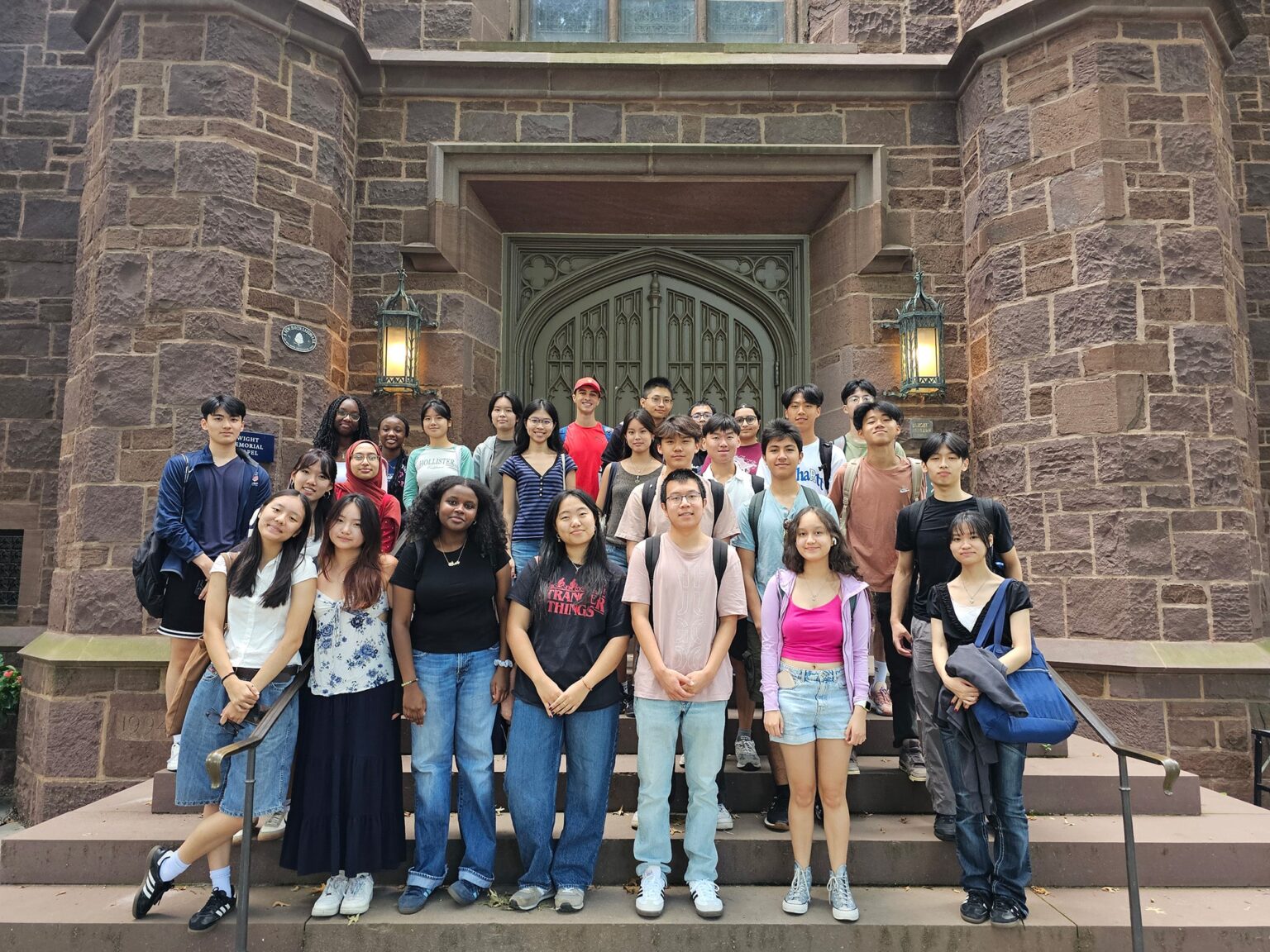 A group of people standing on stairs in front of a old brick building front doors.