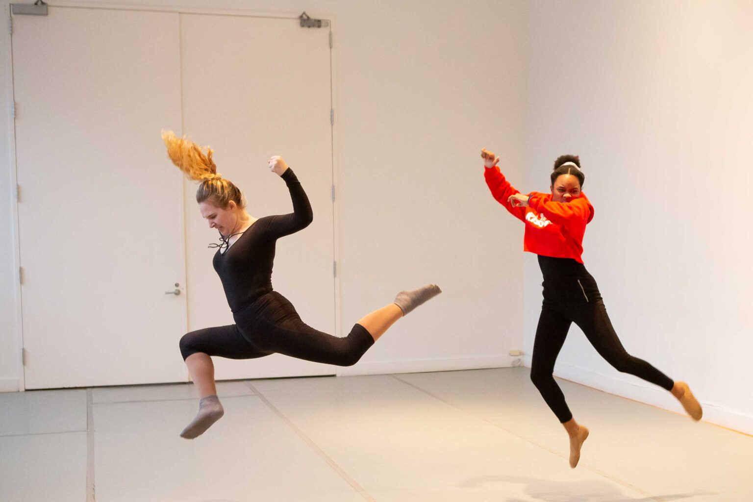 Two woman dance jumping in the air. Anger in their faces and hands in fists.
